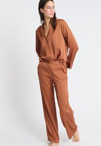 Bruin gestreept pyjama set met een colbert, knoopsluiting en losse broek met een ontspannen silhoutte en een zachte textuur.