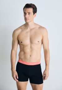 Zwarte boxershorts met een roze Calvin Klein tailleband. De stof is soepel en sluit aansluitend aan het lichaam met minimale naden.