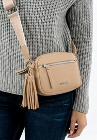 Borsa a tracolla in pelle beige con superficie texturizzata, tasca frontale con zip e dettagli con frange. Cinghia regolabile attaccata per comodità.