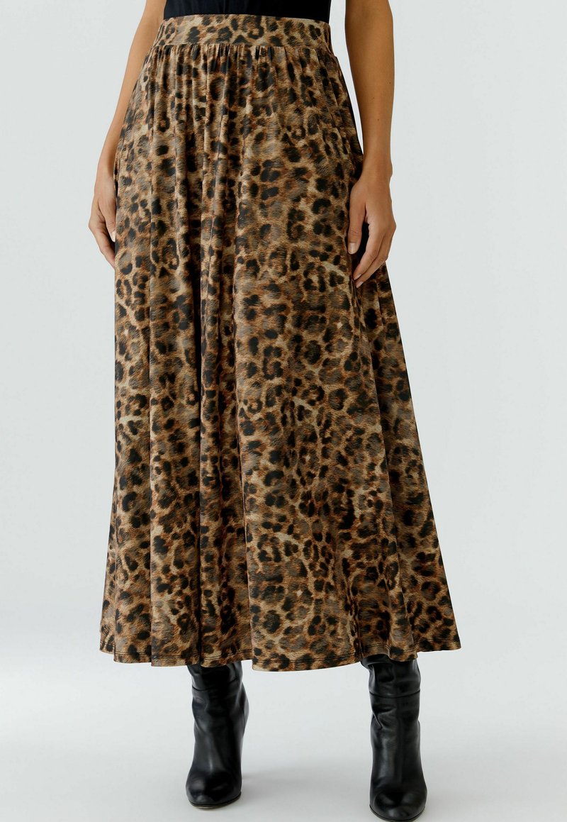 Maxi rok met luipaardprint in een zachte stof, voorzien van een elastische tailleband en een vloeiende silhouette, gecombineerd met zwarte hoge hakken.