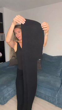 Svarta ribbade leggings hålls vertikalt och visar ett texturerat mönster. Materialet verkar stretchigt och har en jämn yta över hela.