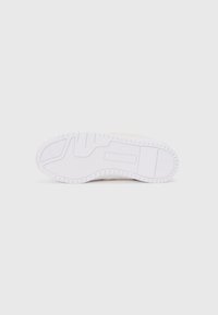 Weiße Gummisohle mit strukturiertem Grip, ausgestattet mit einem glatten Design und eingeprägtem Logo. Obermaterial in Hellbeige mit minimalistischem Schnitt.