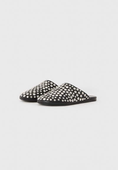Mules noirs avec un dessus en cuir lisse, arborant un motif de points métalliques argentés sur la surface, à dos ouvert et à semelle plate.