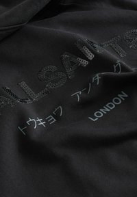 Felpa nera con testo e stampa di paillettes lucide, che include "ALLSAINTS" e "LONDON", su un tessuto morbido e testurizzato.