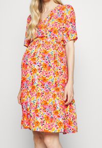 Blumenkleid mit lebhaften Mustern in Pink, Orange und Blau, kurzen Ärmeln und tailliertem Bund für eine fließende Silhouette.
