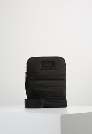 Schwarze rechteckige Umhängetasche mit Reißverschluss, verstellbarem Schulterriemen und kleinem geprägtem Logo-Patch auf der Vorderseite, auf weißem Untergrund präsentiert.