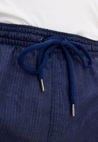 Pantaloni corti blu navy con elastico in vita, dotati di un cordino intrecciato con punte in metallo e un tessuto leggermente strutturato.