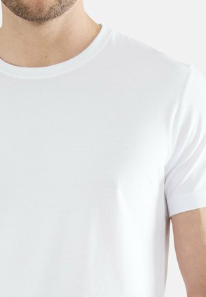 Männlicher Torso trägt ein schlichtes weißes Kurzarm-T-Shirt mit Rundhalsausschnitt vor hellem Hintergrund.