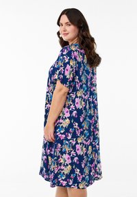 Robe florale avec un fond marine ornée de fleurs roses, jaunes et bleues, à manches courtes et coupe décontractée, tombant au-dessus du genou.
