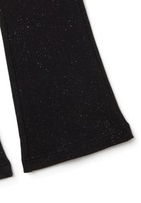 Jambes en tissu noir avec des paillettes argentées, ourlets droits, isolées sur fond blanc.