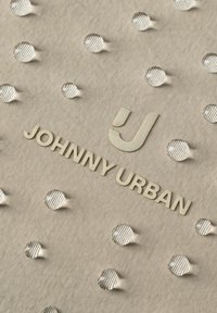 Kangaspinta, jossa on kohotetut pyöreät pisteet ja kohopainettu teksti "JOHNNY URBAN" sekä tyylitelty "J"-logo beigessä sävyssä.