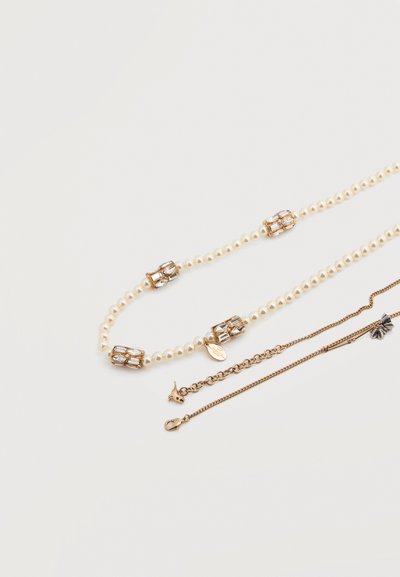 Κολιέ με χάντρες από εκρού μαργαριτάρια, στοιχεία σε χρυσό τόνο και διακοσμητικό κούμπωμα. Περιλαμβάνει μικρότερη αλυσίδα με λεπτομέρεια φιόγκου.