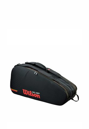 Bolsa de tenis Wilson Pro Staff negra con compartimentos con doble cremallera y asas para transportar, vista lateral en ángulo sobre fondo blanco.