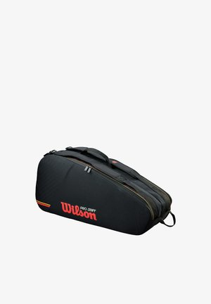 Bolsa de tenis Wilson Pro Staff negra con compartimentos con doble cremallera y asas para transportar, vista lateral en ángulo sobre fondo blanco.