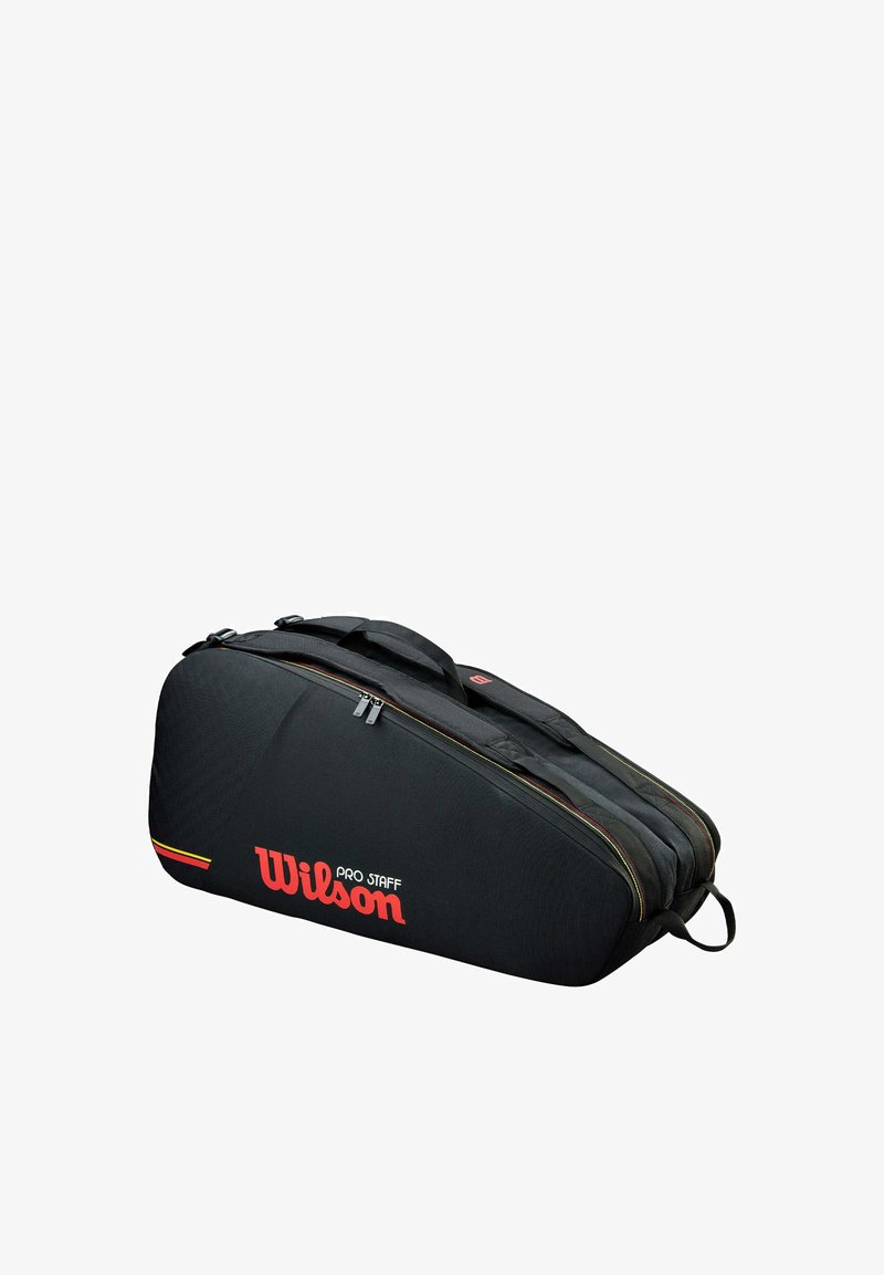 Sac de tennis Wilson Pro Staff noir avec compartiments à double fermeture éclair et poignées, vue latérale en angle sur fond blanc.