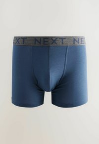 Mörkblå bomullsboxer med ett grått elastiskt midjeband. Midjebandet har varumärket "NEXT" i ett upprepande mönster.