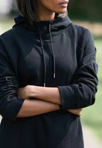 Felpa nera con cappuccio, dal taglio rilassato, caratterizzata da maniche raglan e aghetti metallici sui lacci. Tessuto morbido.