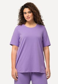 T-shirt viola a maniche corte in un tessuto morbido; presenta un collo rotondo e una vestibilità rilassata. La maglietta è abbinata a pantaloni viola coordinati.