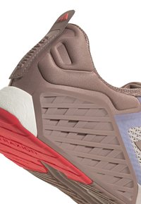 Scarpa sportiva con una tomaia marrone testurizzata, accenti azzurri e una suola rossa con battistrada pattern per una maggiore aderenza.