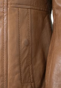 Braune Lederjacke mit sichtbaren Nähten, einer glatten Textur und einer mit Knopf verschlossenen Tasche auf der Vorderseite.