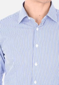 Camicia a righe con bottoni, caratterizzata da sottili linee verticali blu e bianche, colletto a punta e bottoni bianchi lungo la parte anteriore.