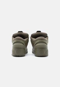 Zaļas gumijas sporta kurpes ar fakturētu virsmu, aprīkotas ar polsterētu apkakli, apaļiem papēžiem un izteiktu logotipa dizainu uz zolītes.