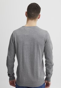 Grå strikket genser med lange ermer, rund hals og ribbestrikkede mansjetter og nederkant. Myk tekstur med en glatt overflate. Vist bakfra.