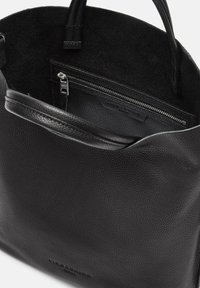 Zwarte leren tote bag met een structuur oppervlak, voorzien van een ritszak en soepele handvatten, van binnen gevoerd met zacht zwart materiaal.