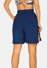 Granatowe szorty wykonane z lekkiego materiału, z elastycznym pasem i kieszeniami, charakteryzujące się gładką fakturą i dopasowanym krojem.