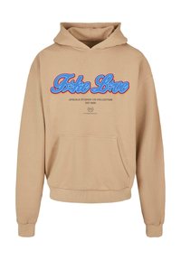 Beige hoodie med blå og rød "Fake Love" tekst, frontkangaroo lomme, og mindre sort tekst med "Upscale Studios 143 Collection EST 2020."