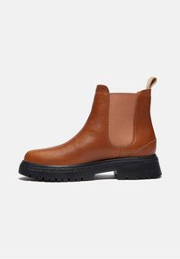 Bottine Chelsea en cuir marron pour homme avec panneaux latéraux élastiques, languette au talon et semelle épaisse en caoutchouc noir.