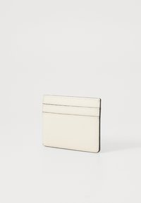 Držač kartica od teksturirane krem kože s četiri utora za kartice, minimalistički dizajn i kontrastno šivanje duž rubova.