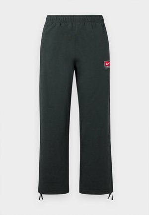 Σκούρο πράσινο παντελόνι Nike με ελαστική μέση, ίσια πόδια, μικρό κόκκινο και λευκό λογότυπο Nike στο μηρό και ρυθμιζόμενα κορδόνια στα μπατζάκια.