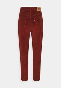 Pantalon en velours côtelé rouge à coupe droite, avec deux poches arrière et une étiquette en cuir de marque à la taille. Texture douce avec un motif côtelé.