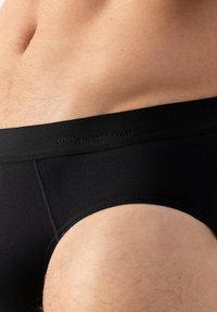 Schwarze Baumwoll-Boxershorts mit einem glatten Bund, dezentem Markenlogo und einer engen Passform um Hüften und Oberschenkel.