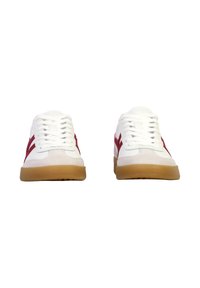 Zapatillas blancas con rayas laterales rojas, cordones blancos y suelas de goma, vistas desde el frente sobre un fondo blanco.