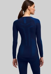 Sportowa koszulka z długim rękawem w ciemnym granacie, ozdobiona teksturowanym wzorem z różnymi motywami i niebieskimi akcentami. Dopasowana, z prążkowanymi mankietami.