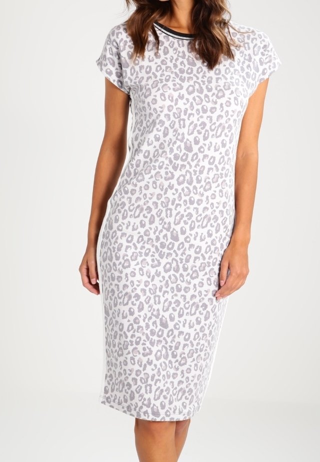 Femme portant une robe ajustée mi-longue, manches courtes, imprimé léopard gris clair et col rond bordé de noir.