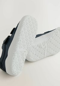 Marineblauwe kinderschoenen met klittenbandsluitingen en een getextureerde witte rubberen zool met een visgraatpatroon voor grip.