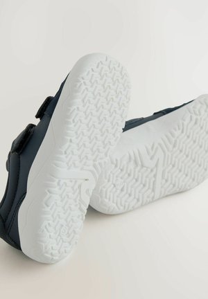 Marineblaue Kinderschuhe mit Klettverschluss und einer strukturierten weißen Gummisohle mit Fischgrätmuster für besseren Halt.