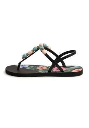 Sandalia plana negra con suela estampada con flores, tiras delgadas y cuentas decorativas azules, beige y doradas en la tira entre los dedos.