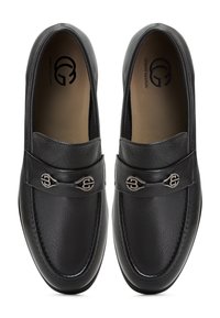 Černé kožené mokasíny s texturovaným svrškem, prošívanými detaily a kovovými logo akcenty na tónovém pásku. Hladká vnitřní podšívka.