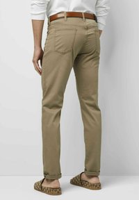 Khaaki-Hosen mit slim fit, ausgestattet mit fünf Taschen und einem braunen Gürtel. Der Stoff ist leicht mit einer glatten Textur. Hochgekrempelte Säume sind sichtbar.