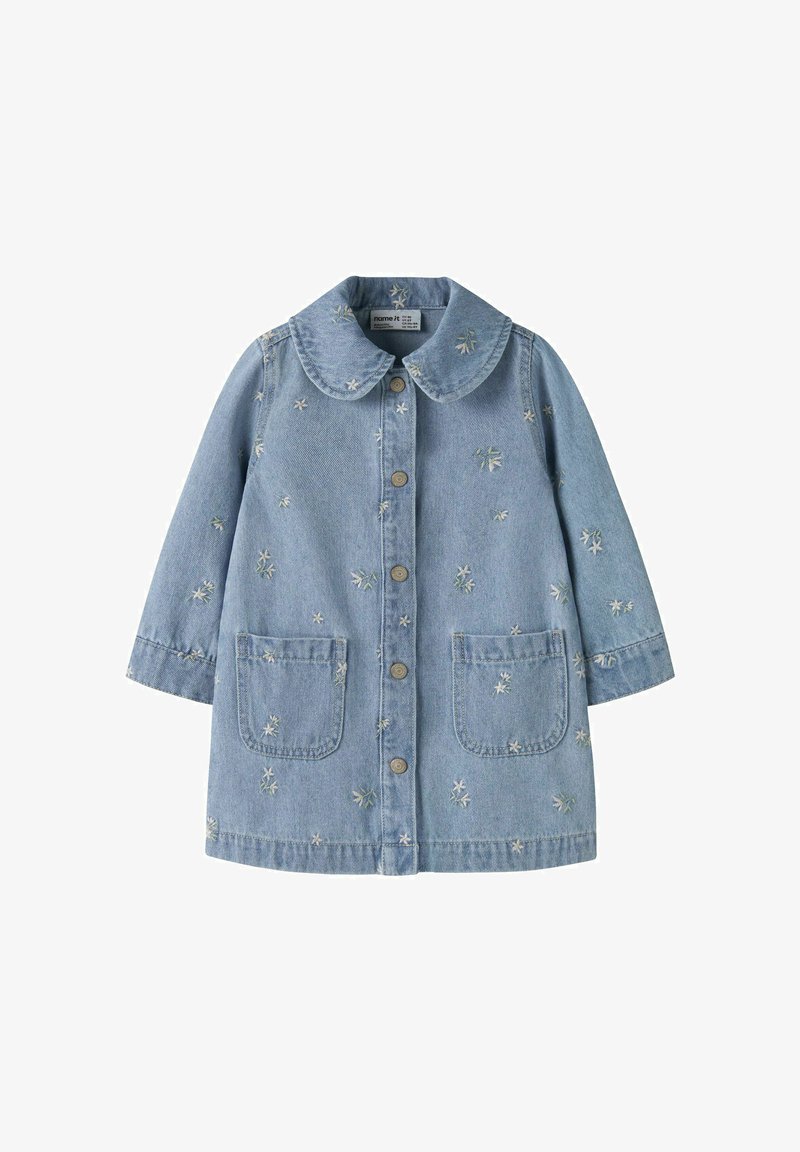 Denimjakke i lys blå farge, med stor krage, frontknapper, to påsydde lommer og broderte blomsterdekorasjoner over hele jakken.