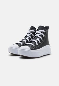 Sneakers alte con una toma nera testurizzata, lacci bianchi e punta in gomma bianca. Presentano una suola bianca spessa con scanalature verticali.