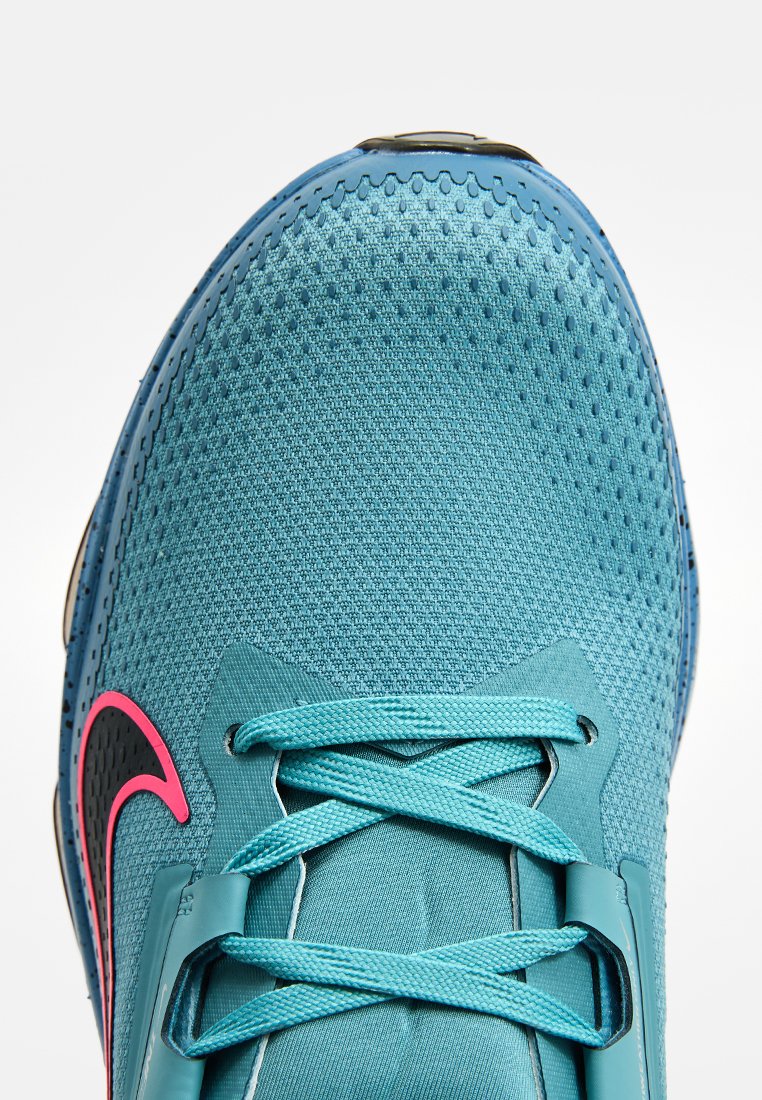 Turkusowe buty sportowe z siateczkowego materiału, z refleksyjnymi akcentami i różowym logo. Posiadają płaskie sznurówki oraz teksturowaną powierzchnię zapewniającą przyczepność.