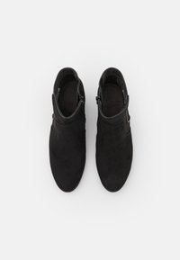 Botas de tobillo negras de ante suave, con una superficie lisa, punta ligeramente afilada y una cremallera lateral para facilitar su uso.