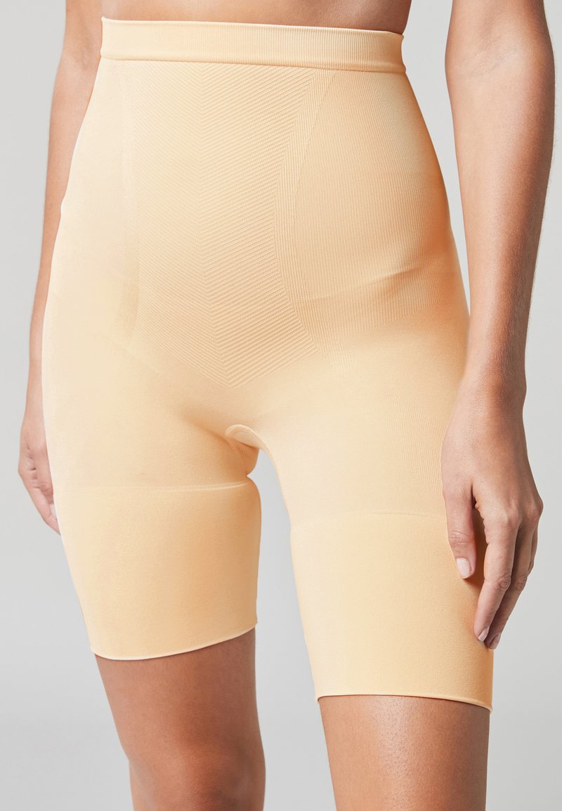 Shorts modellanti beige a vita alta realizzati in un materiale liscio e elasticizzato, con un design senza cuciture e una sottile texture a righe.