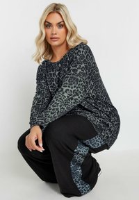 Haut à manches longues en imprimé léopard dans des tons de gris foncé et noir, associé à un pantalon noir avec un panneau latéral en imprimé léopard assorti.