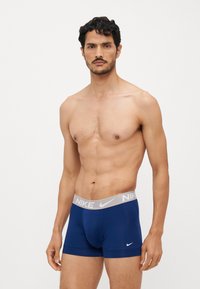 Tamnoplave bokserice sivi pojas s Nike logom. Izrađene su od rastezljivog materijala za udobnost i prilagođeni dizajn.